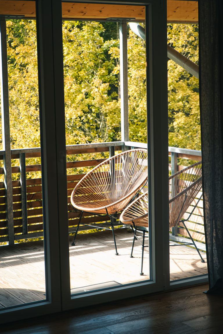 Blick auf einen Balkon mit Stühlen und Wald im Hintergrund