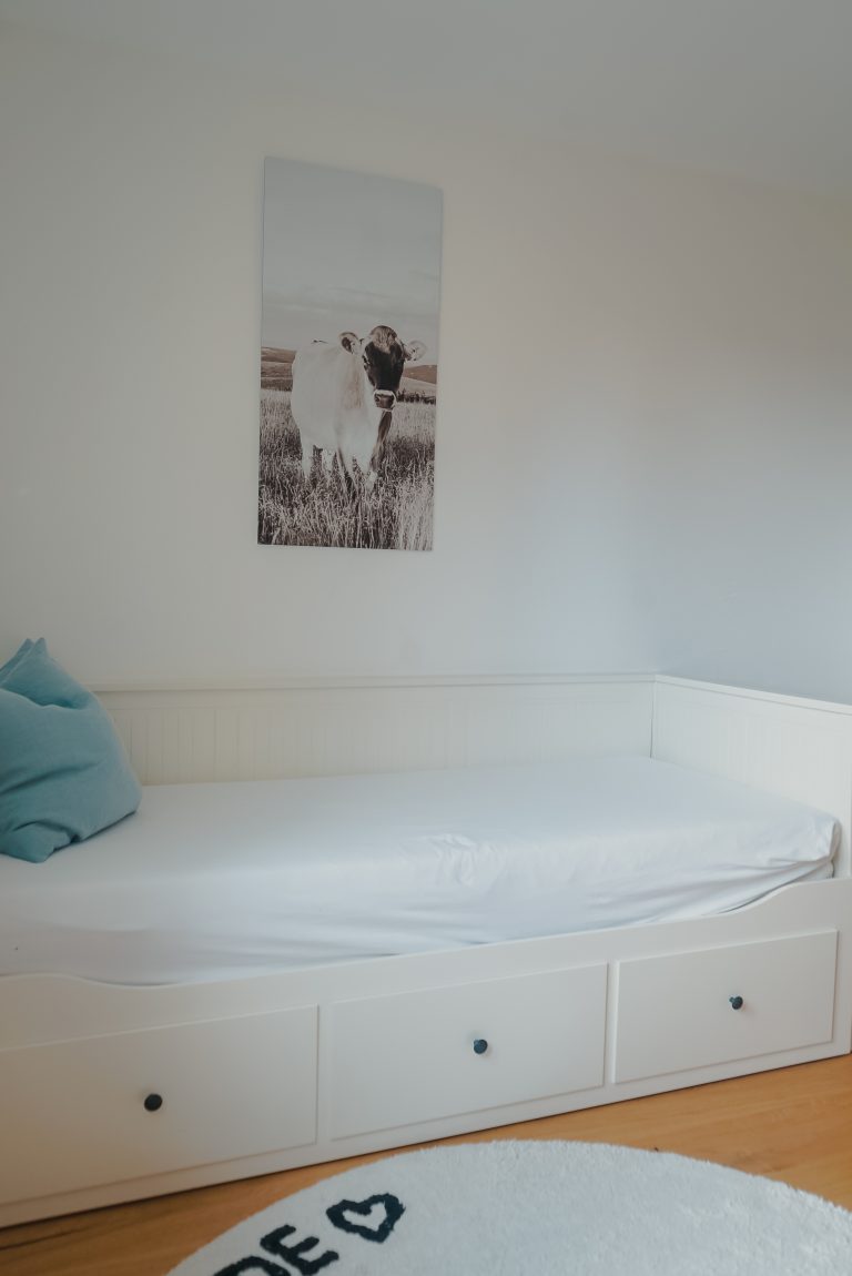 Ein weißes Schlafsofa mit einem Bild einer Kuh im Hintergrund